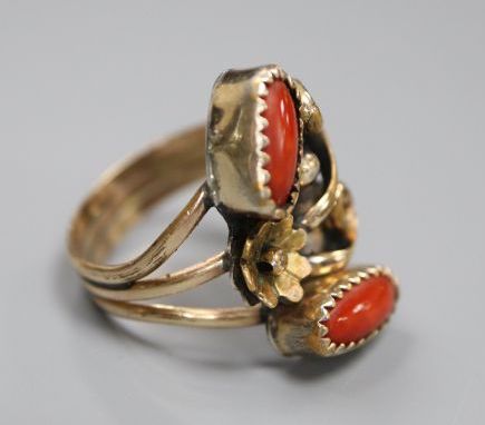An Arts & Crafts yellow and white metal and two stone cabochon coral set triple shank dress ring, size O,